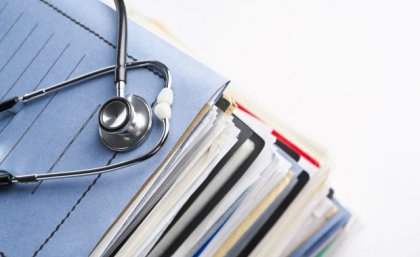 a stethoscope sits on top of a pile of files